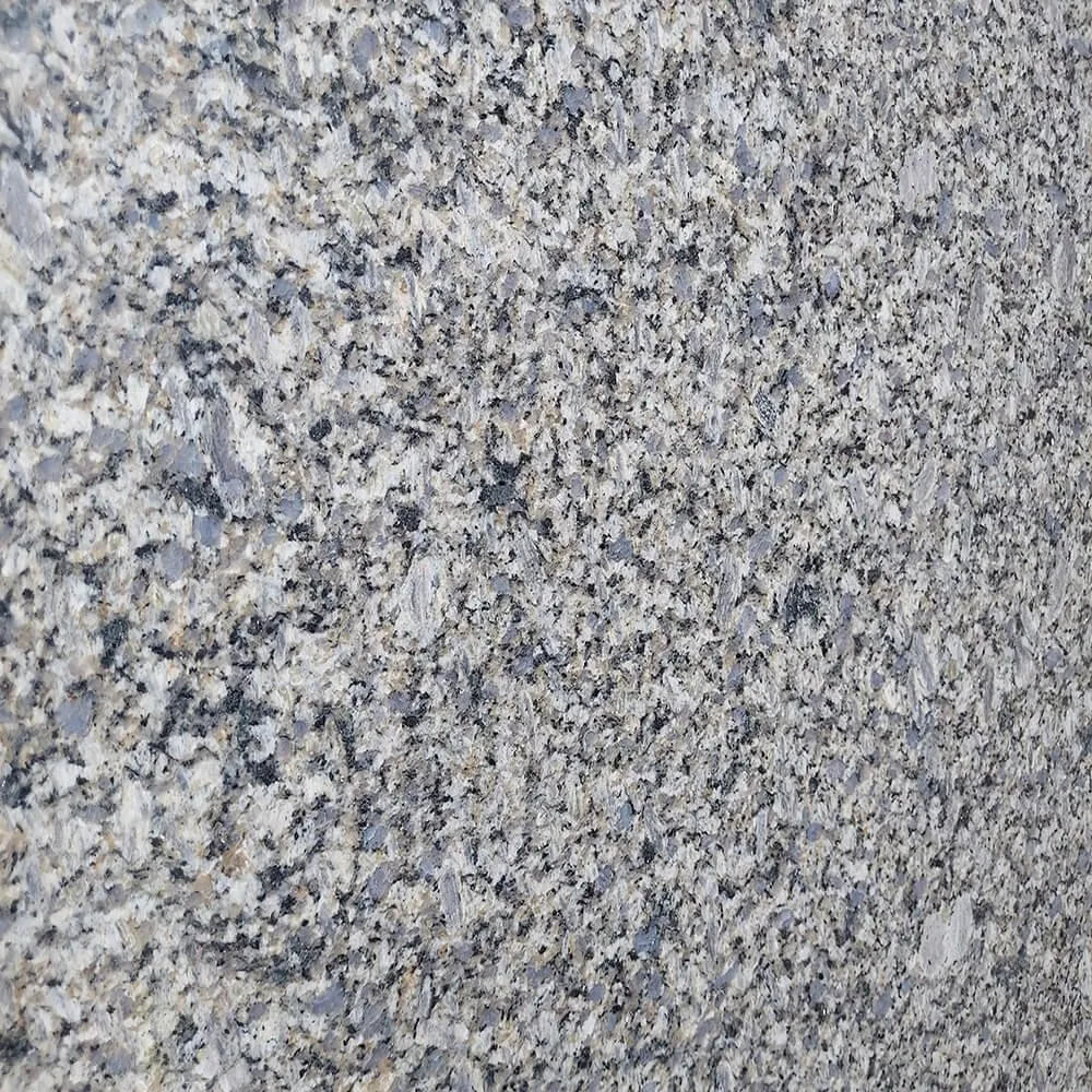 Close-up of Vizag Blue Granite slab, featuring a fine-grained texture with shades of blue, grey, and white minerals. Used for comparison to show the more granular nature of other blue granites vs the swirling energy of Himalayan Blue.